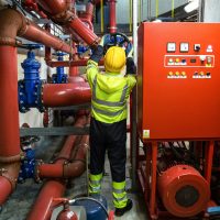 Worker in uniform operates machinery in industrial setting, emphasizing safety and productivity.