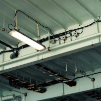 Electrical Services Detailed view of industrial ceiling light and wiring at a low angle in an indoor setting.