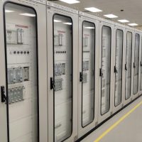 Electrical Services View of an industrial control room featuring rows of electrical panels in a well-lit environment.