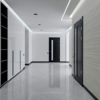 Electrical Services Wide corridor in modern house with white tiled walls and floor black wooden doors and shelves for storage built in wall